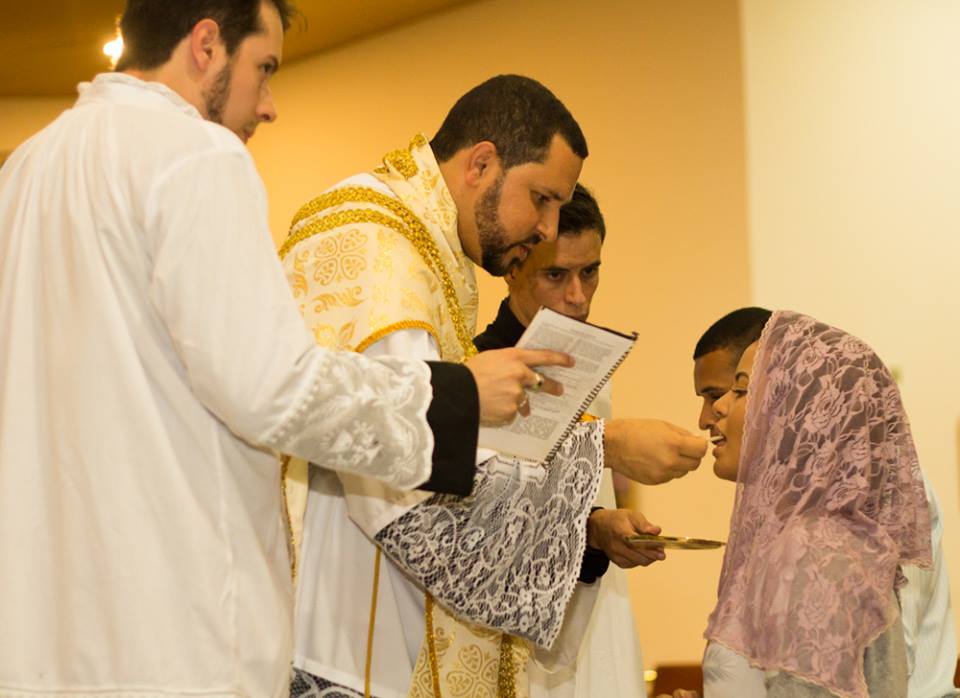 Fiel recebe Sagrada Eucaristia das mãos do Pe. Michel